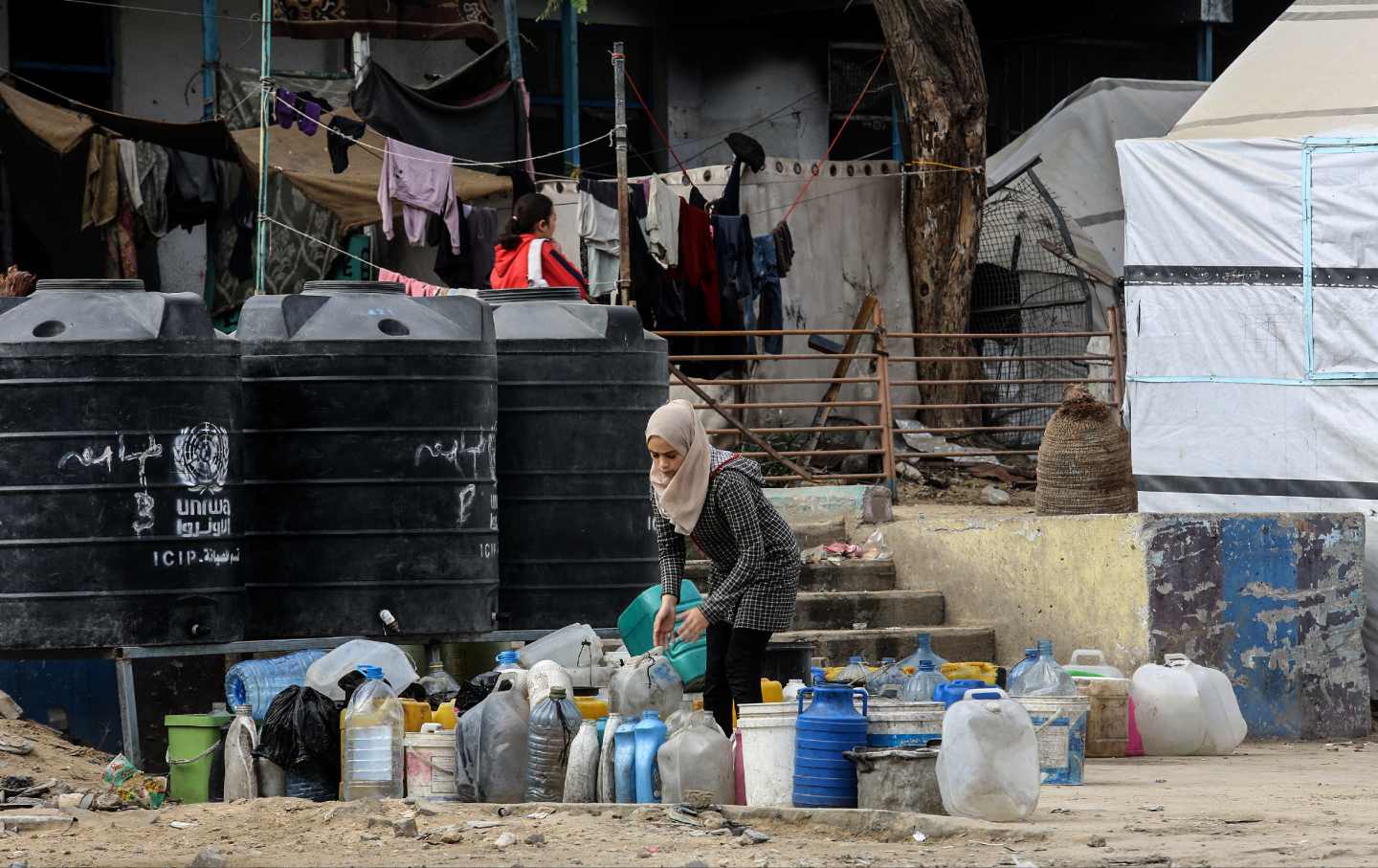 Seorang wanita mengatur botol kosong saat warga Palestina yang mengungsi berjuang untuk bertahan hidup sementara serangan Israel berlanjut di Khan Yunis, Gaza pada 18 November 2024.