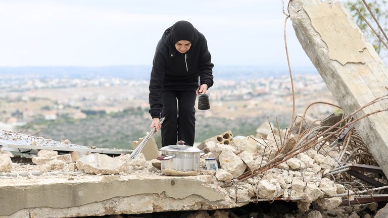 Seorang wanita Lebanon yang mengungsi berdiri di atas puing-puing dekat rumahnya yang hancur di Zibqin, Lebanon selatan. Foto: Reuters