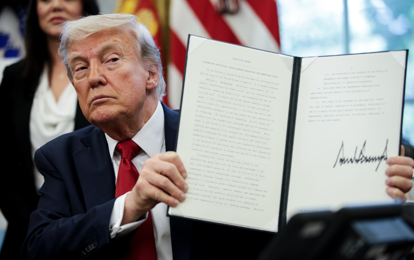 Donald Trump menampilkan perintah eksekutif yang ditandatangani di Kantor Oval Gedung Putih di Washington, DC.