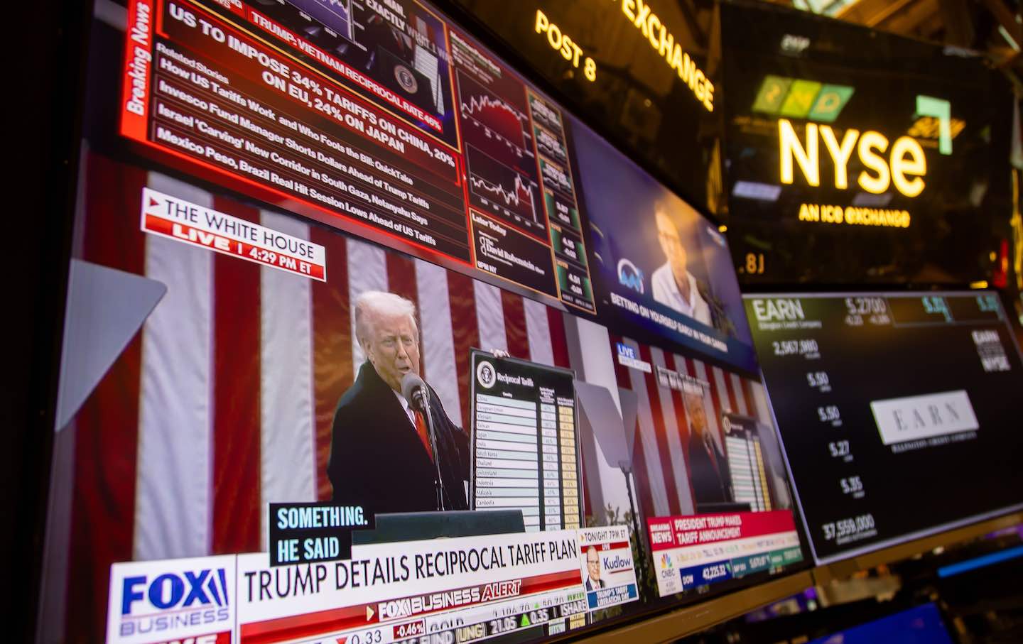 Sebuah stasiun televisi di lantai Bursa Efek New York menyiarkan Donald Trump mengumumkan tarif.