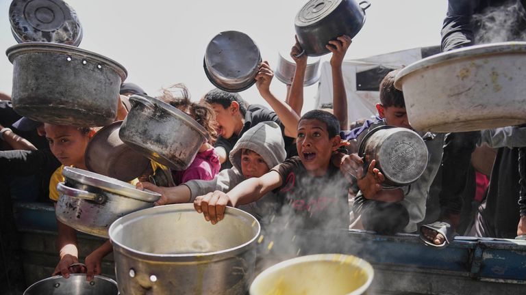 Anak-anak Palestina berjuang untuk mendapatkan makanan yang disumbangkan di dapur komunitas di Khan Younis, Jalur Gaza, Sabtu, 3 Mei 2025. (AP Photo/Abdel Kareem Hana)