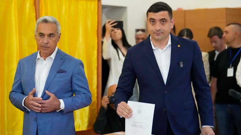 Kandidat presiden George Simion (kanan) memberikan suaranya di sebelah Calin Georgescu. Foto: AP/Vadim Ghirda