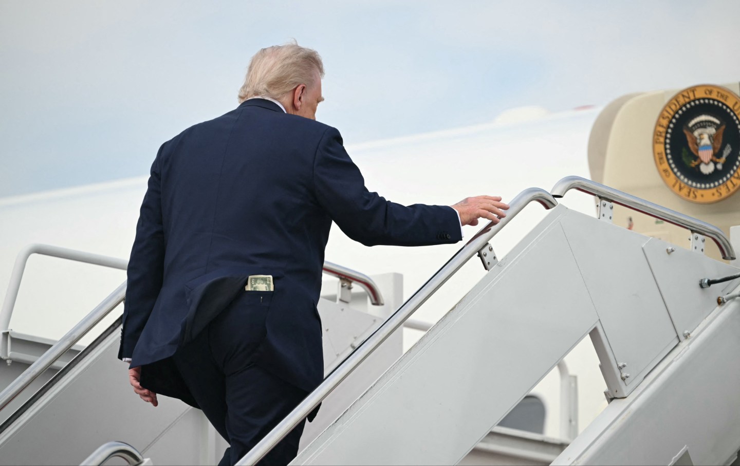 Uang lima puluh dolar terlihat di saku belakang Presiden AS Donald Trump saat dia naik ke Air Force One sebelum berangkat dari Pangkalan Bersama Andrews di Maryland, pada 1 Mei 2025.