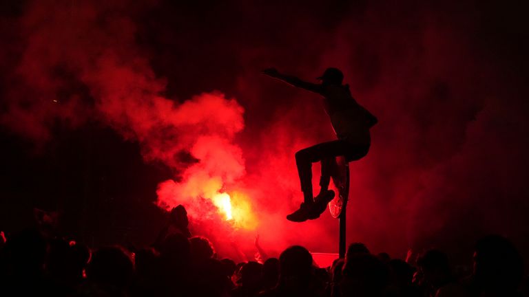 Seorang pendukung PSG di rambu lalu lintas di Paris sementara suar merah dinyalakan setelah tim memenangkan Liga Champions. Foto: AP