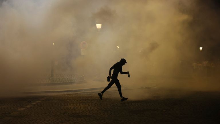 Seorang pria berjalan melewati gas air mata selama insiden setelah pertandingan final sepak bola Liga Champions antara Paris Saint-Germain dan Inter Milan. Foto: AP