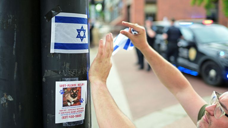 Seorang pria menjepit tongkat bendera Israel ke tiang di dekat lokasi serangan. Foto: Reuters
