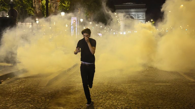 Seorang pria melarikan diri dari gas air mata selama insiden di Champs Elysees Avenue setelah PSG memenangkan Liga Champions. Foto: AP