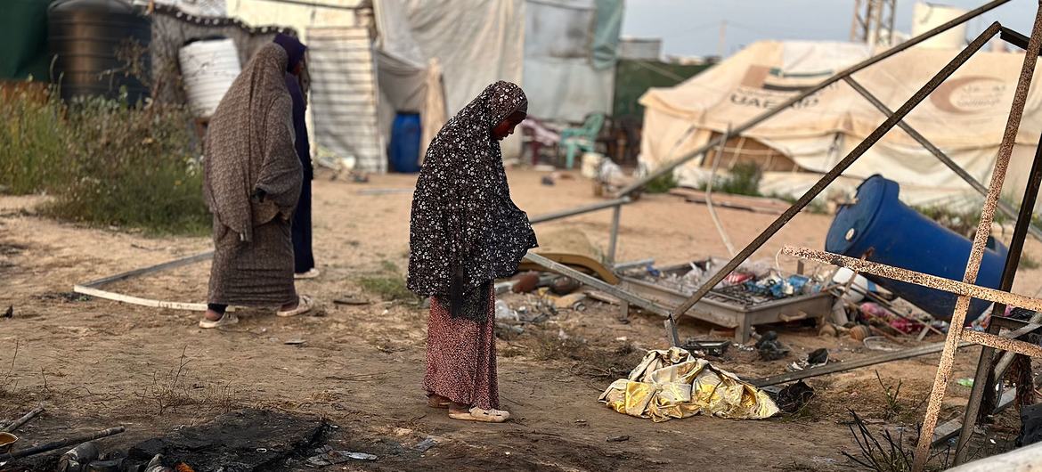 Perempuan berdiri di pemukiman pengungsian yang rusak di Khan Younis, Gaza.