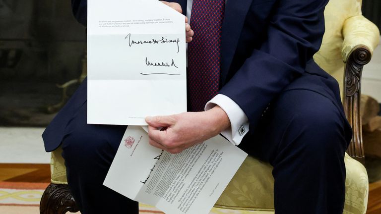 Presiden AS Donald Trump memegang surat dari Raja Inggris Charles saat dia bertemu dengan Perdana Menteri Inggris Keir Starmer (tidak dalam foto) di Kantor Oval di Gedung Putih di Washington, DC, AS, 27 Februari 2025. REUTERS/Kevin Lamarque