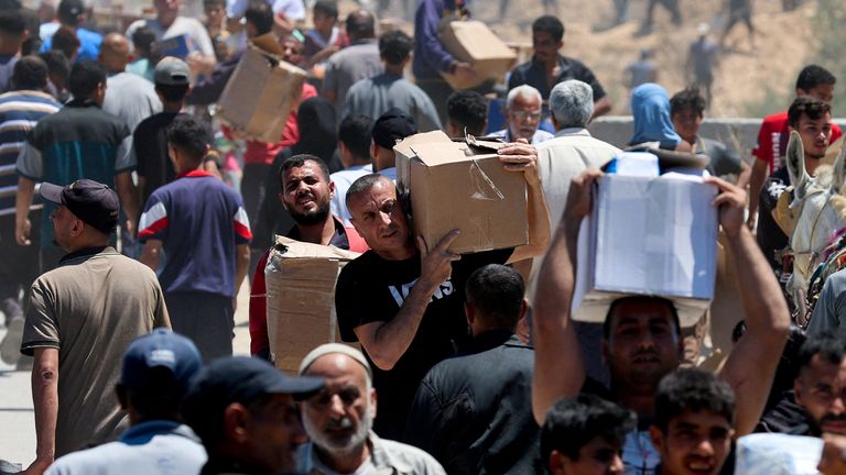 Warga Palestina membawa pasokan bantuan yang mereka terima dari GHF yang didukung AS, di Jalur Gaza tengah, 29 Mei. Foto: Reuters