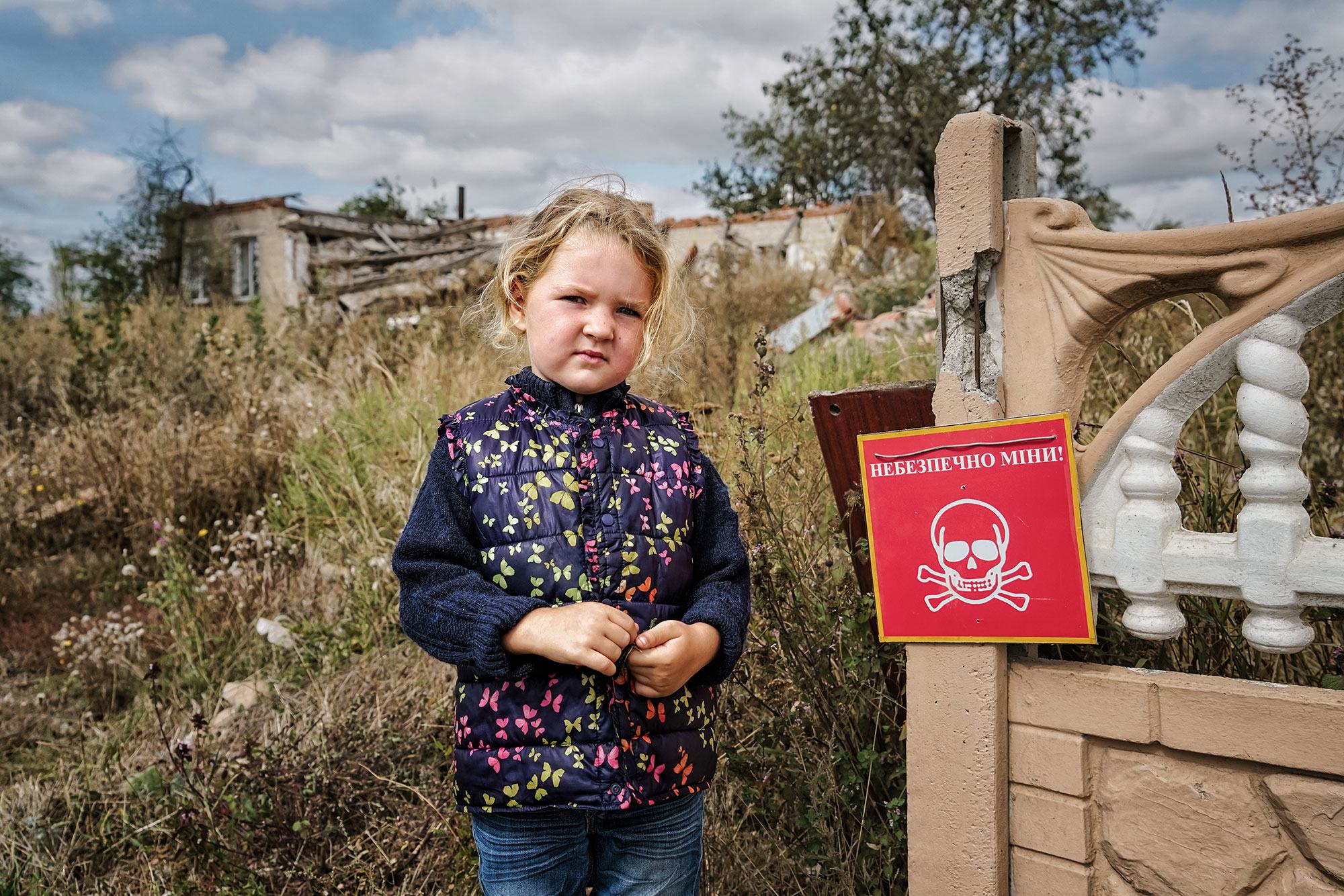 Veronika, 4, berdiri di dekat tanda yang bertuliskan "Bahaya Ranjau". Chistovodivka, wilayah Kharkiv, Ukraina (file, Mei 2025) Veronika, 4, berdiri di dekat tanda yang bertuliskan "Bahaya Ranjau". Chistovodivka, wilayah Kharkiv, Ukraina (file, Mei 2025)