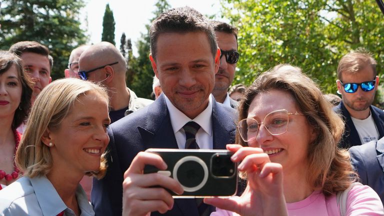 Rafal Trzaskowski berpose untuk selfie dan meninggalkan tempat pemungutan suara bersama istrinya Malgorzata Trzaskowska. Foto: AP