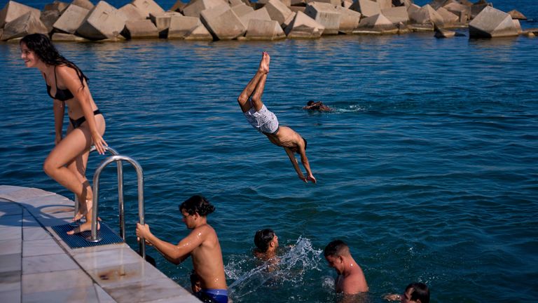 Perenang melompat ke air pada hari yang panas di Barcelona, Spanyol, Selasa, 1 Juli 2025. (AP Photo/Emilio Morenatti)