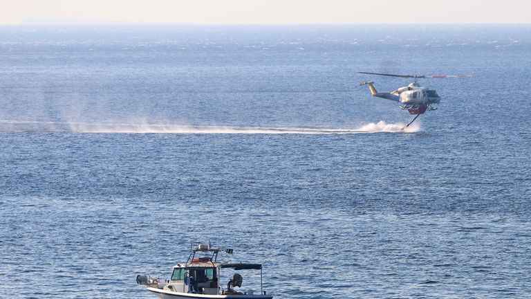 Sebuah helikopter pemadam kebakaran mengambil air dari laut, saat kebakaran hutan membakar di dekat Lerapetra, di pulau Kreta, Yunani. Foto: Reuters