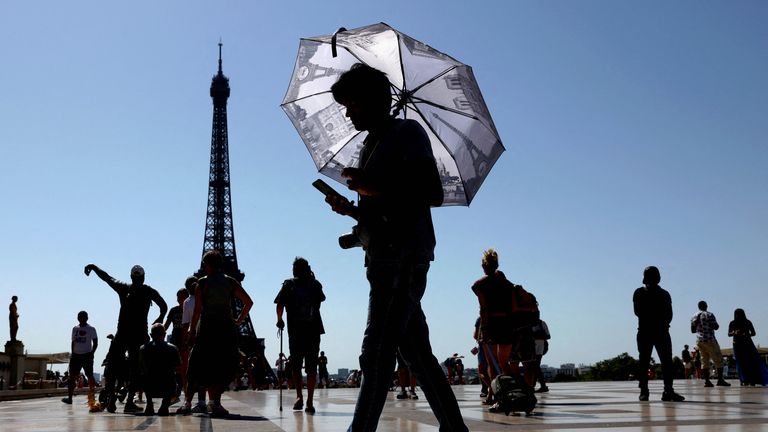 Seorang turis yang memegang payung untuk melindungi dirinya dari sinar matahari berjalan di alun-alun Trocadero di sebelah Menara Eiffel. Foto Reuters