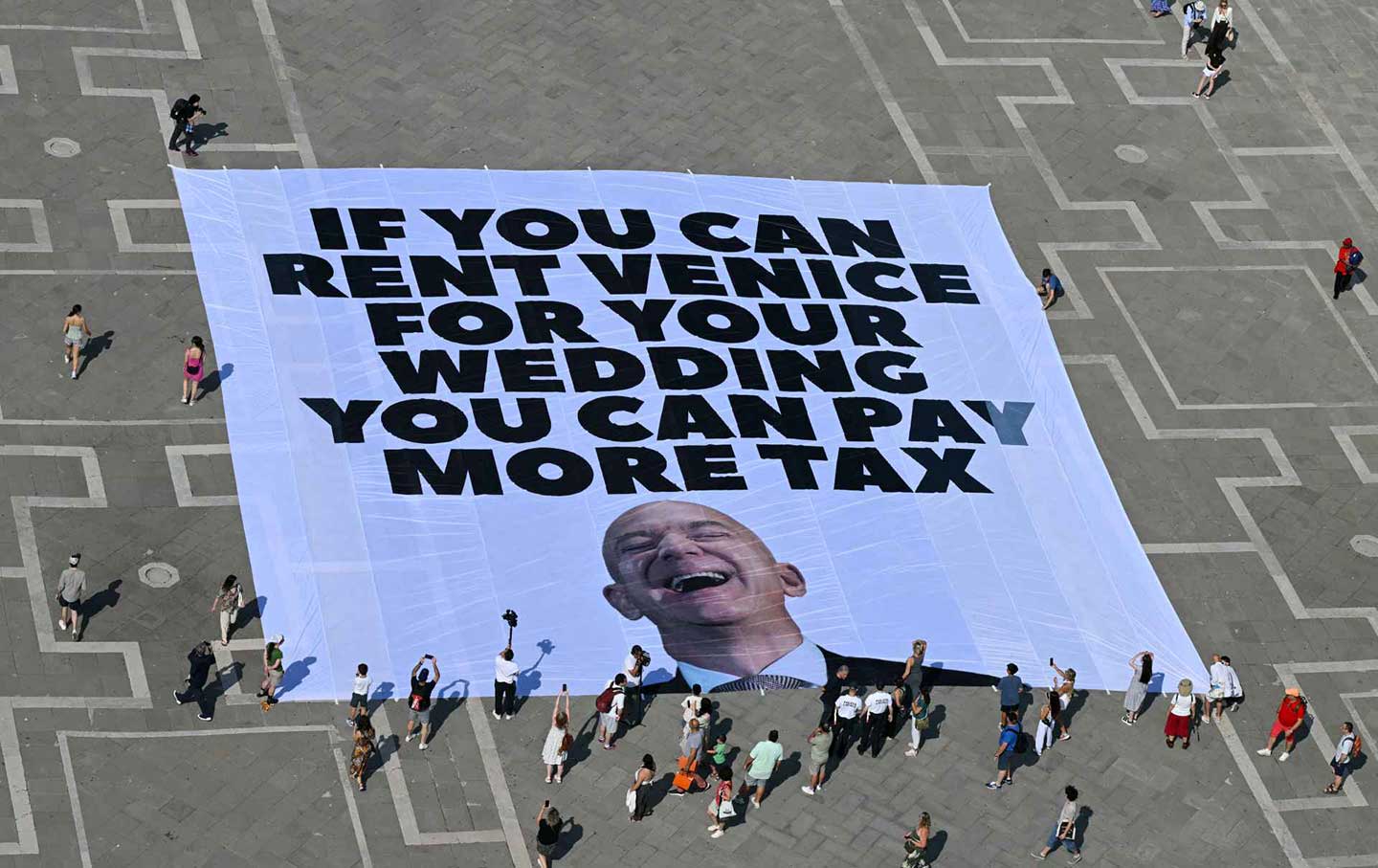 Aktivis Greenpeace mengerahkan spanduk raksasa di Lapangan St. Mark di Venesia pada 23 Juni 2025.