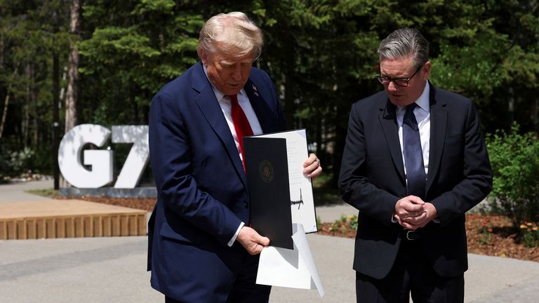 Presiden AS Donald Trump memegang perjanjian yang ditandatangani INGGRIS-AS perjanjian perdagangan selama pertemuan dengan Perdana Menteri Inggris Keir Starmer, pada KTT G7, di Kananaskis, Alberta, Senin, 16 Juni 2025. (Suzanne Plunkett/Foto Kolam renang melalui AP)